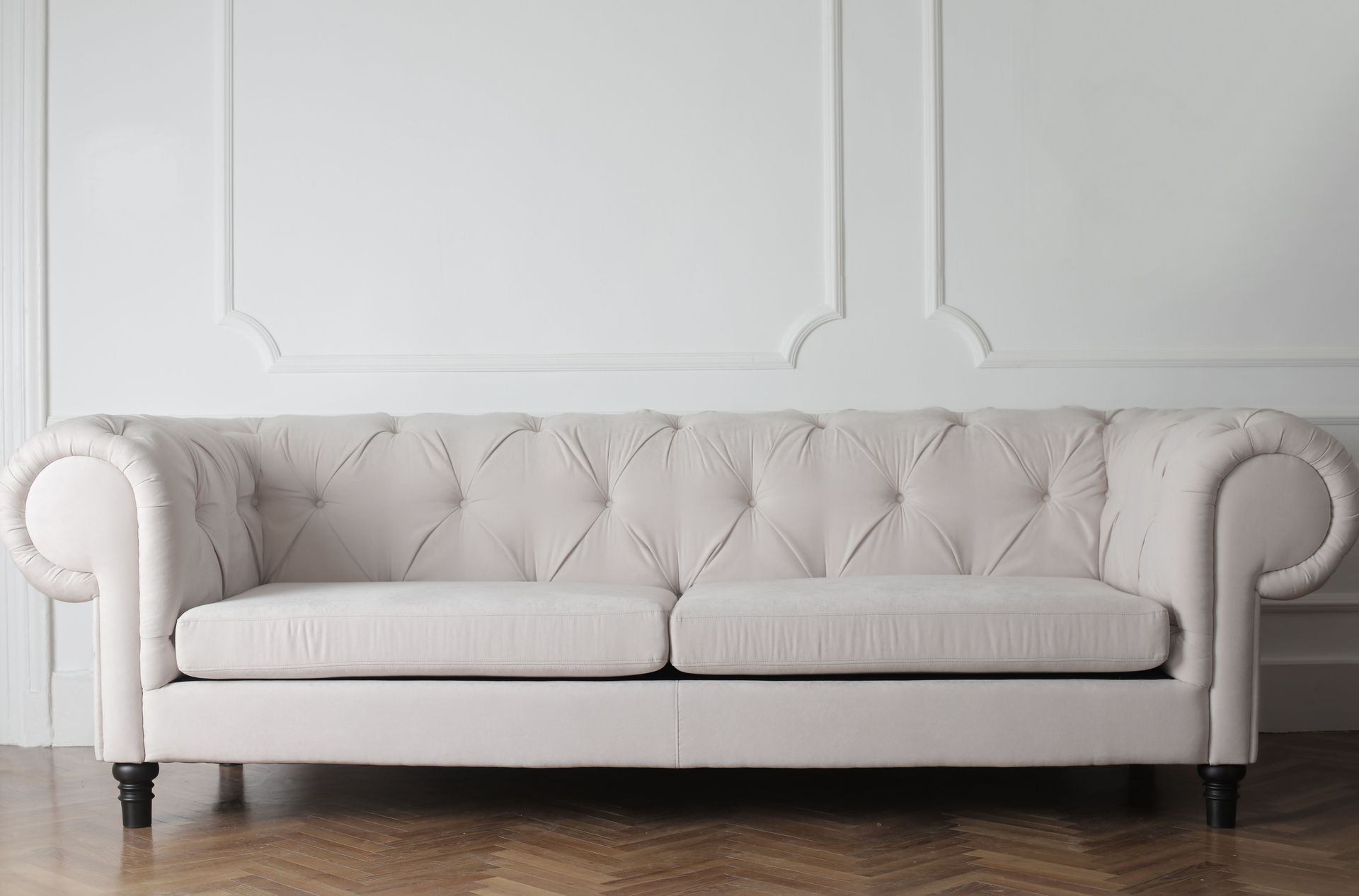 Luxurious white sofa in a modern minimalist interior with wooden flooring.
